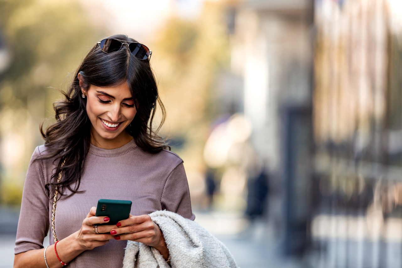 Shot of a beautiful mature businesswoman texting. Mature businesswoman walking outdoors and using cellphone. Female business professional walking outside and texting from her mobile phone.