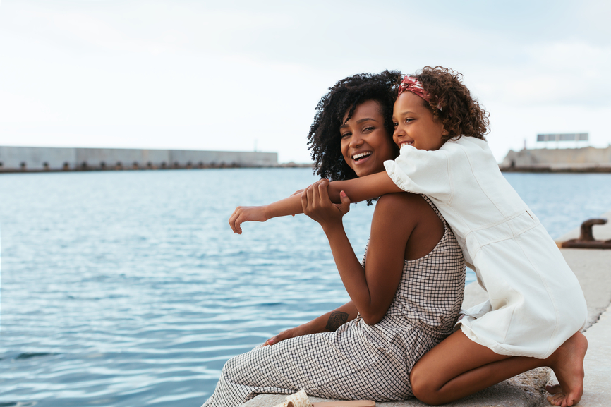 Mother and daughter sitting by the waterside